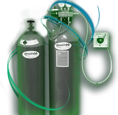 The Green CO2 Systems high-pressure micro bulk CO2 system: two tall green high pressure cylinders with Green CO2 labels, a gauge manifold on top and an outside fill box on the wall.